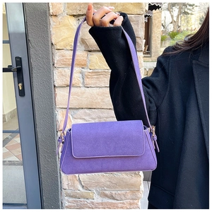 Detail of purple matte suede underarm bag featuring elegant gold metal buckles and flap design