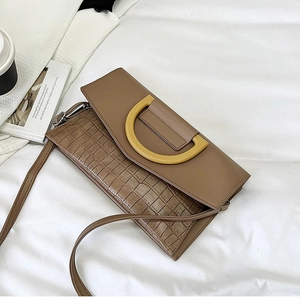 Detail shot of brown crocodile pattern handbag with yellow D-shaped metal decoration
