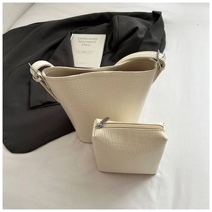 Close-up of ivory bucket bag with crocodile texture and matching mini zipper pouch
