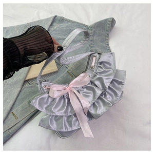 Detail of silver-purple satin handbag featuring ruffle edges and a soft pink bow accent
