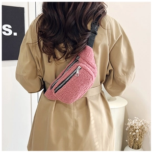 Detail of pink teddy fleece crossbody bag featuring dual silver zippers and nylon strap