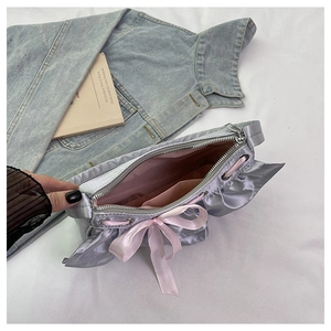 Detail of silver-gray satin bag showing pink bow, inner lining, and metal zipper closure