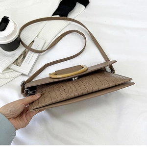 Detailed side view of brown faux leather bag featuring crocodile texture and round top handle