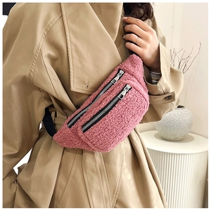 Pink fleece teddy waist bag with metal double zippers shown on a khaki trench coat