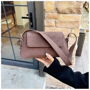 Detail of coffee brown matte suede shoulder bag with wide strap in outdoor lighting