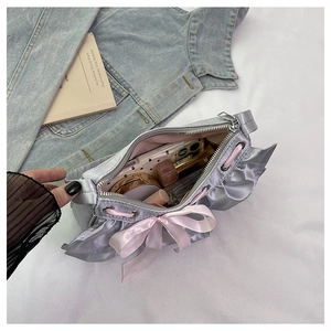 Detail view of silver satin bag interior showing space for phone and makeup with bow