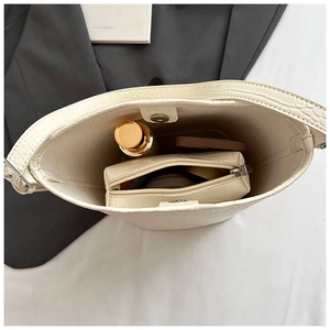 Interior view of beige crocodile embossed bucket bag with inner pouch and cosmetics