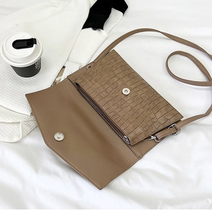Detailed interior of dark brown crocodile pattern clutch showing zipper compartment and strap