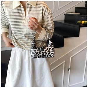 Woman holding leopard print glossy tote bag in a stylish interior staircase setting
