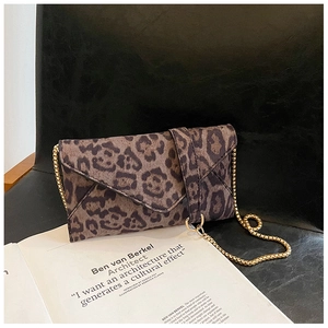 Close-up of leopard print envelope clutch bag with gold chain strap on an armchair
