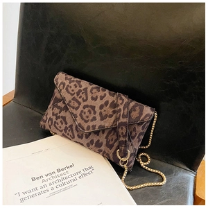 Detailed close-up of leopard print envelope clutch bag with golden metal chain strap