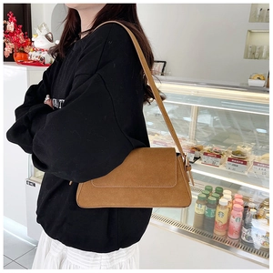 Detailed view of brown matte suede underarm bag with adjustable buckle strap on model