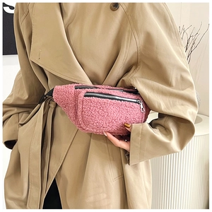 Close-up of pink teddy plush fanny pack with dual black zippers on khaki trench coat