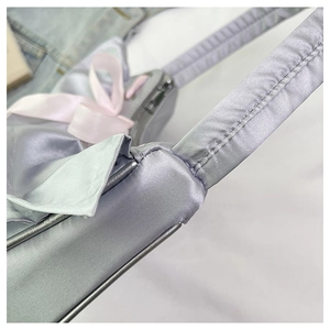 Detail of lavender satin bag with pink silk bow showing fine stitching and smooth texture