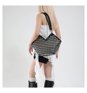 Détail d'un sac cabas en cuir noir avec rivets argentés porté par un mannequin punk