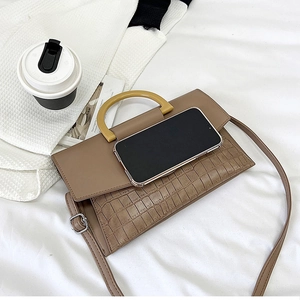 Detail of tan crocodile embossed texture bag with yellow handle and smartphone for size