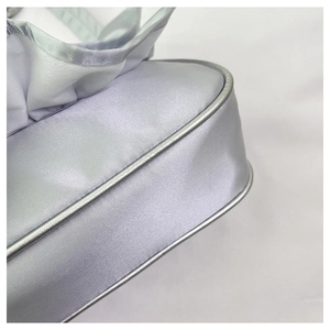 Detail shot of the ruffled silver satin fabric and piping on the elegant handbag