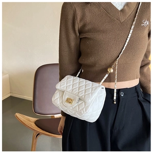 Detailaufnahme einer weißen gesteppten Ledertasche mit goldener Schließe und Kette