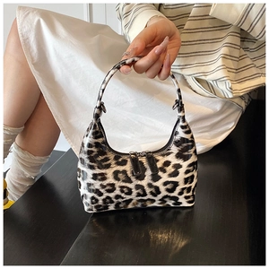 Detail of glossy leopard print patent leather handbag with dual zipper closure and metal buckle
