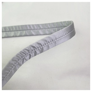Macro shot of silver satin shoulder strap featuring detailed double stitching and pleated texture
