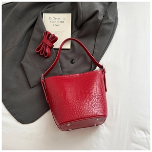 Detailed close-up of red crocodile pattern bucket bag with bottom metal rivets