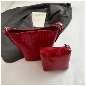 Detail of red crocodile texture bucket bag and matching coin purse set on fabric