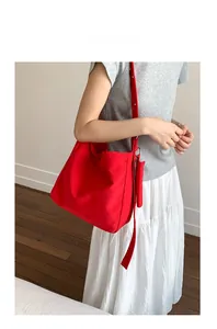 Detailed shot of a red canvas tote bag showing capacity and style on a female model