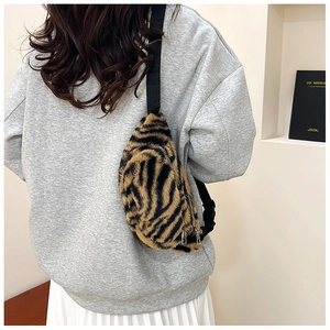 Detail of tiger pattern plush crossbody bag with adjustable strap and metal zippers