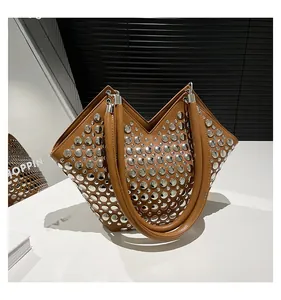 Détail du sac en cuir marron avec rivets métalliques argentés et poignée cylindrique