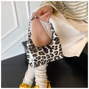 Close-up of glossy patent leather handbag featuring classic leopard print and dual zippers