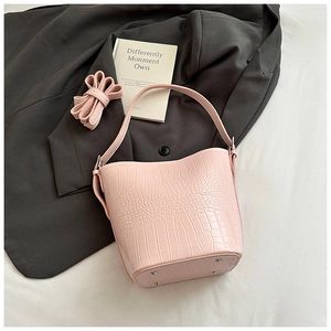 Detailed view of light pink crocodile pattern bucket bag with metal protective feet