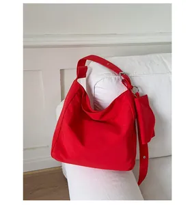 Detail of red canvas hobo tote bag with matching mini pouch on shoulder strap