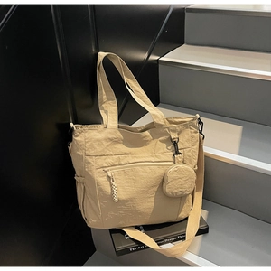 Detail of khaki nylon tote bag featuring front zipper pocket and round mini pouch attachment