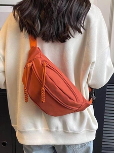 Achteraanzicht van een model met een feloranje nylon crossbodytas met dubbele rits