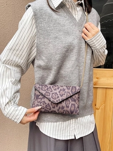Fashionable leopard print envelope clutch with gold chain strap worn by a model