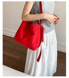 Detail of red canvas tote bag with adjustable wide strap and matching mini pouch accessory