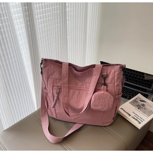 Detail of light pink nylon tote bag showing its water-resistant texture and side drawstring pocket