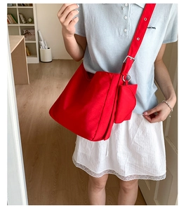 Detail of red canvas shoulder bag with adjustable eyelet strap and small round coin purse