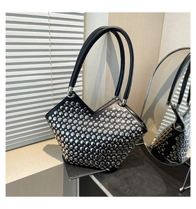 Détail du sac cabas en cuir noir avec rivets argentés denses et coupe en V sur le dessus