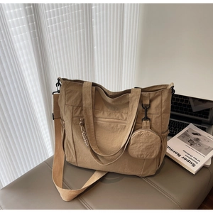 Detail view of khaki nylon tote bag with side pockets and a round coin purse charm