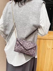 Fashion leopard print envelope crossbody bag with gold chain strap shown on a model