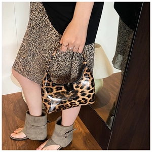 Detail of leopard print patent leather crescent bag shown with stylish casual outfit