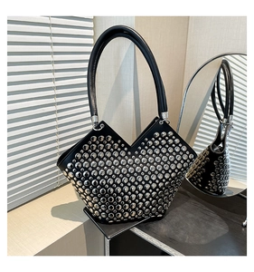 Détail d'un sac cabas noir avec rivets argentés et poignée supérieure en forme de V
