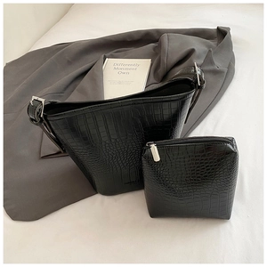 Detailed view of black crocodile pattern bucket bag with silver hardware and small pouch