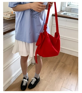 Detailed view of large red canvas tote bag worn by a model in a minimalist kitchen setting