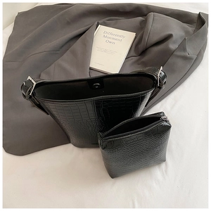 Detail of black crocodile texture bucket bag and matching pouch on elegant background