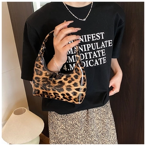 Close-up of shiny leopard print handbag featuring high-gloss patent leather and dual zippers