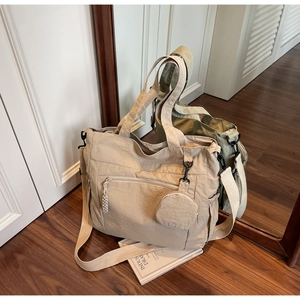 Detail view of large nylon tote bag with round coin purse attachment and canvas strap
