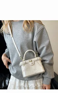 Detail of cream vintage faux leather handbag with pocket design and adjustable strap