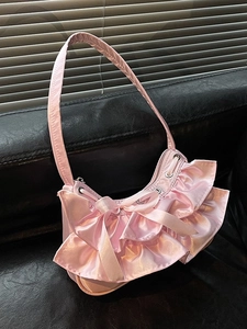 Pink satin crescent underarm bag with layered ruffles and bow decoration in soft lighting